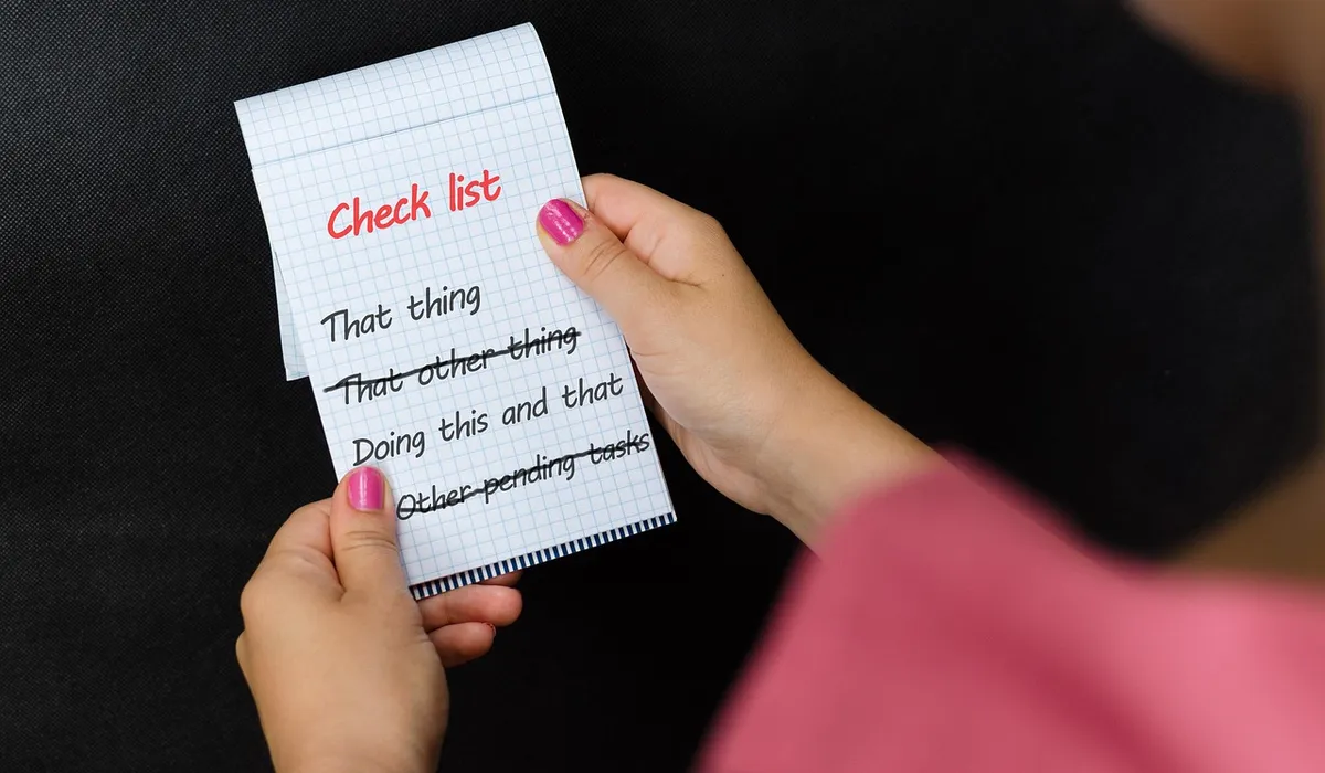 Close-up of hands holding a small checklist card with a red 'Check list' heading