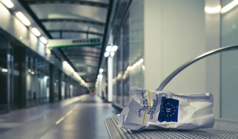 Airport terminal corridor with a sealed package on a metal bench, blurred background suggesting travel preparation.