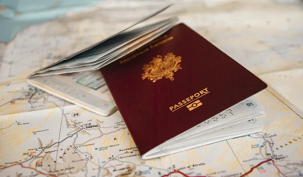 A burgundy passport and scattered travel documents resting on a world map, symbolizing the paperwork involved in taking a parrot abroad.